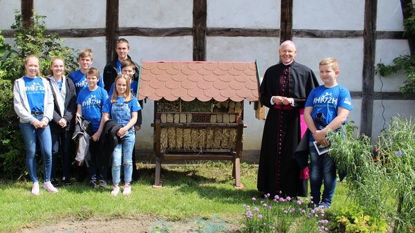 Jugendliche und Weihbischof vor der Wildbienennisthilfe