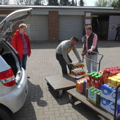 Männer laden Lebensmittel aus dem Auto auf Einkaufswagen