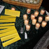 Kerzen und Zettel mit Fürbitten auf einem Tisch